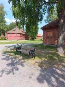 Benk med to bygg i bakgrunnen